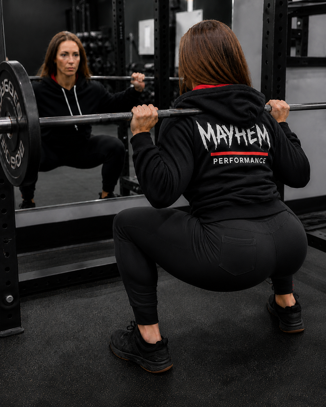 Athlete wearing a 'Mayhem Performance' hoodie squatting in a gym.